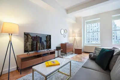 a living room with a couch and a flat screen tv at FiDi Studio w Residents Bar Golf Simulator Gym NYC-271 in New York