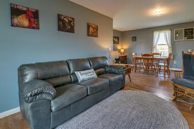 a living room with a leather couch and a dining room at Upstate New York Vacation Rental Near Cooperstown! in Cherry Valley