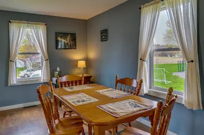 a dining room with a table and chairs and two windows at Upstate New York Vacation Rental Near Cooperstown! in Cherry Valley
