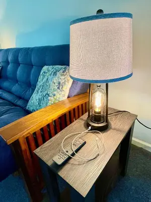 a lamp and remote controls on a table with a couch at Walk to the Outfield of Lime Rock Park in Salisbury