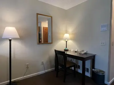 a room with a desk with a mirror and a lamp at The Central Downtown Inn Suites in Pittsfield
