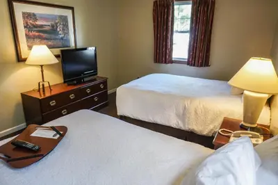a hotel room with two beds and a flat screen tv at The Central Downtown Inn Suites in Pittsfield