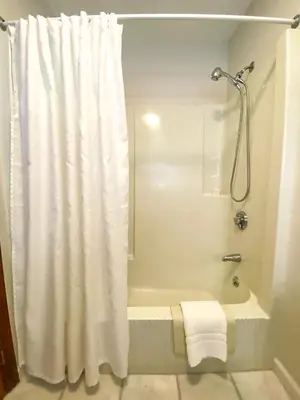a bathroom with a shower curtain and a bath tub at The Central Downtown Inn Suites in Pittsfield