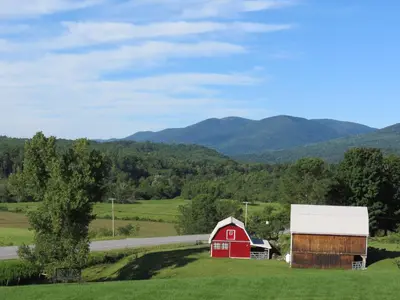 a red barn in a field with mountains in the background at North Shire Lodge in Manchester