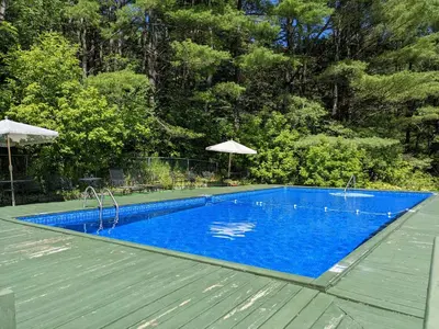 a large blue swimming pool with a wooden deck at North Shire Lodge in Manchester