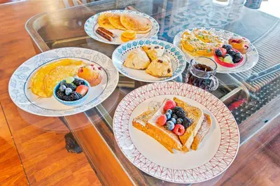 a glass table with plates of breakfast food on it at North Shire Lodge in Manchester