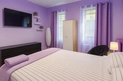 a bedroom with a large bed with purple walls at Lavender style Room in Geusthouse in New York