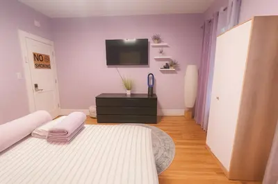 a bedroom with a bed and a tv on the wall at Lavender style Room in Geusthouse in New York