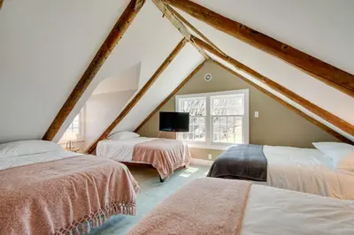a attic bedroom with two beds and a window at Serene Retreat Near Mt Snow Great for Groups! in Marlboro