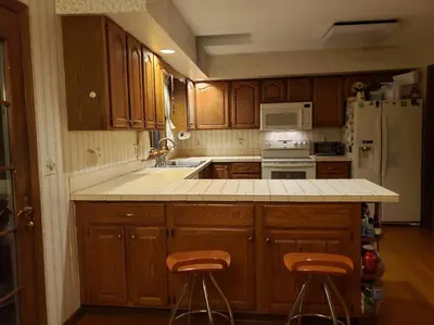 a kitchen with wooden cabinets and a kitchen counter with stools at Charming mountain view country house in Cheshire
