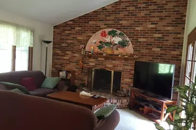 a living room with a brick wall and a television at Charming mountain view country house in Cheshire
