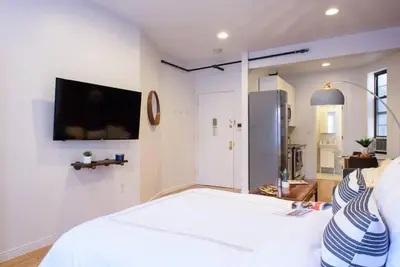 a bedroom with a white bed with a tv on the wall at 83-3W UES Central Park Newly Furnished XL Studio in New York