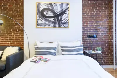 a bedroom with a bed and a brick wall at 83-3W UES Central Park Newly Furnished XL Studio in New York