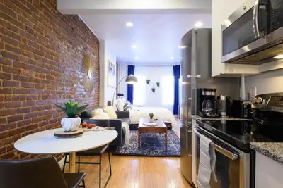 a kitchen and living room with a brick wall at 83-3W UES Central Park Newly Furnished XL Studio in New York