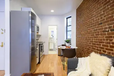 a kitchen and a living room with a brick wall at 83-3W UES Central Park Newly Furnished XL Studio in New York