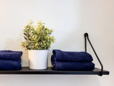 a shelf with two blue towels and a plant at Stylish studio in Bristol, newly renovated! in Bristol