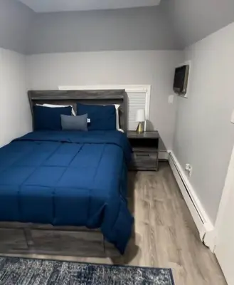 a bedroom with a blue bed and a desk at Cozy Studio with 1 Bed & Comfy Sofa Bed in New Rochelle