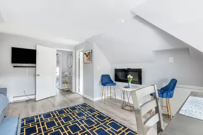 a living room with a table and blue chairs at Cozy Studio with 1 Bed & Comfy Sofa Bed in New Rochelle