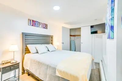 a white bedroom with a large bed and a table at Walk to Downtown Albany Ten Broeck Triangle Apt! in Albany