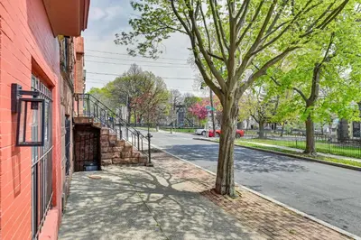a tree on a sidewalk next to a red building at Walk to Downtown Albany Ten Broeck Triangle Apt! in Albany