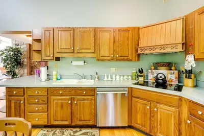 a kitchen with wooden cabinets and a stainless steel dishwasher at Spacious Woodbury Home with Pool and Hot Tub! in Woodbury