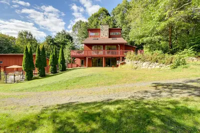 a large red house on a large grass field at Spacious Woodbury Home with Pool and Hot Tub! in Woodbury