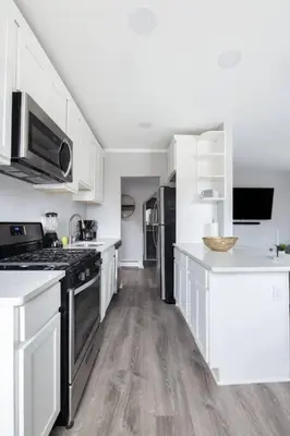 a kitchen with white cabinets and a stove top oven at Sleek 1 Bedroom Apartment Plus Balcony 30 Mins to NYC in New Rochelle