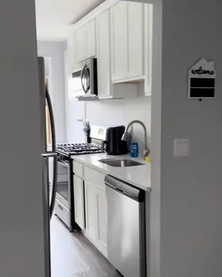 a kitchen with white cabinets and a sink and a refrigerator at Sleek 1 Bedroom Apartment Plus Balcony 30 Mins to NYC in New Rochelle