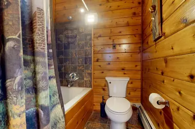 a wooden bathroom with a toilet and a bath tub at Mountain View Chalet in West Dover