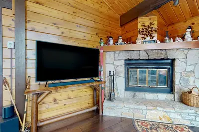 a large flat screen tv in a living room with a fireplace at Mountain View Chalet in West Dover