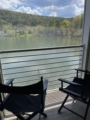 two chairs on a porch with a view of a lake at Lake Front Hotel in Cooperstown