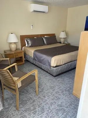 a bedroom with a bed and a chair and two lamps at Lake Front Hotel in Cooperstown