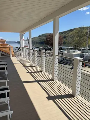 a wooden porch with white railing and chairs on a marina at Lake Front Hotel in Cooperstown