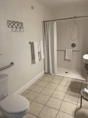 a white bathroom with a shower and a toilet at Lake Front Hotel in Cooperstown