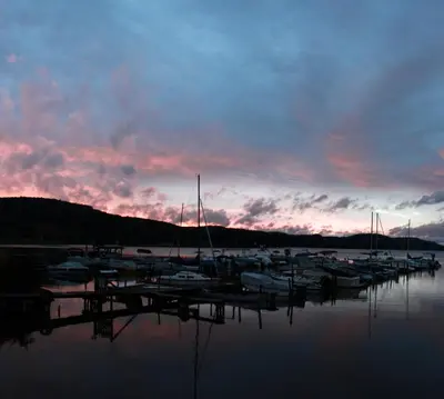 a group of boats docked at a marina at sunset at Lake Front Hotel in Cooperstown