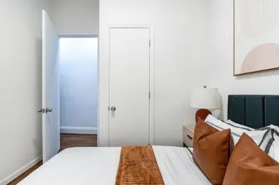 a bedroom with a bed with white sheets and a chair at 91-1D 3BR 2baths Duplex with a Private Back yard - GYM in New York