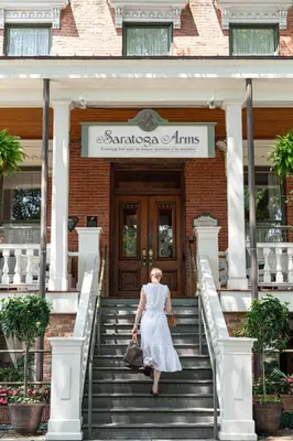 a woman walking up the stairs to the entrance to a building at Saratoga Arms Hotel in Saratoga Springs