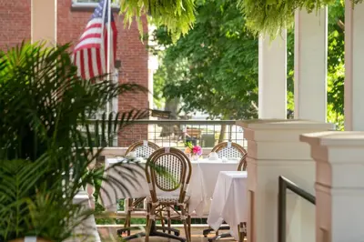 a table with chairs and an american flag on a porch at Saratoga Arms Hotel in Saratoga Springs