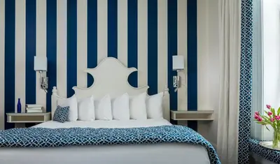 a bedroom with a bed with blue and white stripes at Saratoga Arms Hotel in Saratoga Springs
