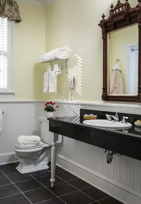 a bathroom with a toilet and a sink and a mirror at Saratoga Arms Hotel in Saratoga Springs