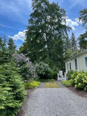 a garden with a house and some flowers at Cozy 2-bedroom Cottage with Access to Bantam Lake in Morris