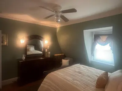 a bedroom with a bed with a ceiling fan and a mirror at 2Br Private Victorian Apartment in City location on half acre Sleeps 5 in Poughkeepsie