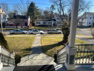a porch with a white fence and cars on a street at 2Br Private Victorian Apartment in City location on half acre Sleeps 5 in Poughkeepsie