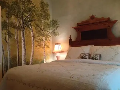 a bedroom with a bed with trees on the wall at The White House Inn in Cooperstown