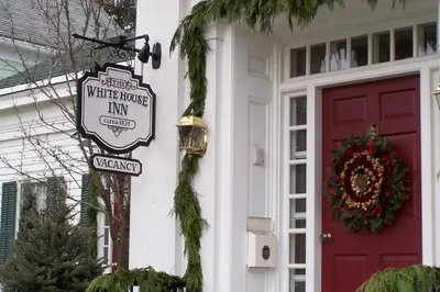 a house with a red door and a white house inn sign at The White House Inn in Cooperstown