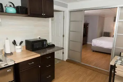 a kitchen with a microwave and a room with a bed at Knotty Pine Motel in Bennington