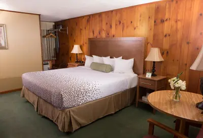 a bedroom with a large bed and wooden walls at Knotty Pine Motel in Bennington