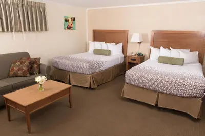a hotel room with two beds and a couch at Knotty Pine Motel in Bennington