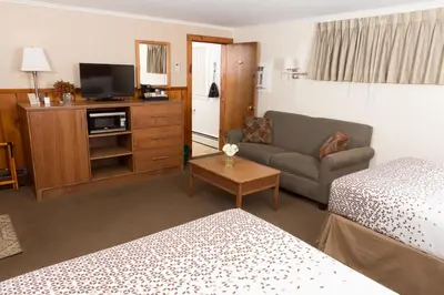 a hotel room with a bed and a couch and a tv at Knotty Pine Motel in Bennington