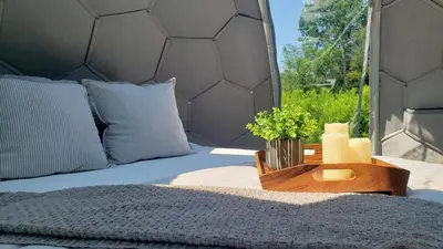 a bed in a tent with a table with flowers on it at Battenkill Glamping Resort in Cambridge